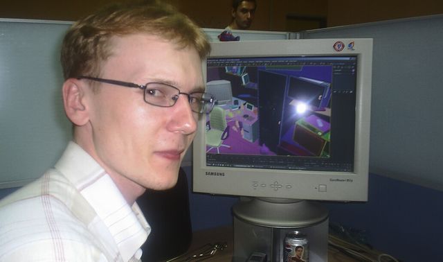 Evgeniy (KraiSoft team member) is looking at the camera while a 3D editor is open on his PC