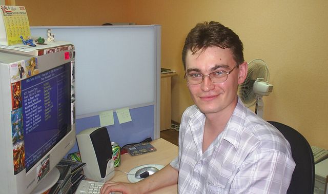 Denis (KraiSoft team member) is sitting next to his computer and smiling at the camera